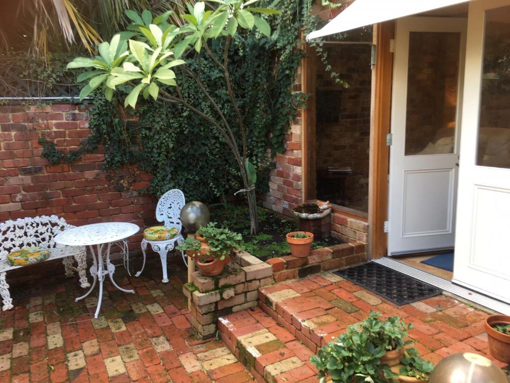 un patio con mesa, sillas y plantas en Gorgeous studio 2 minutes from the heart of Subiaco en Perth