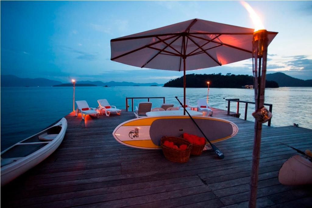 a boat sitting on a dock with an umbrella at Pousada Casa do Bicho Preguiça in Angra dos Reis