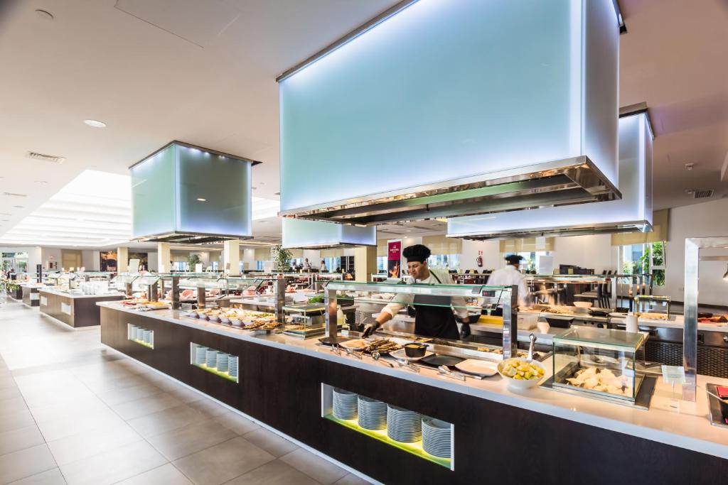 a kitchen with a buffet line with people preparing food at Royal Palm Resort & Spa - Adults Only in Playa Jandia