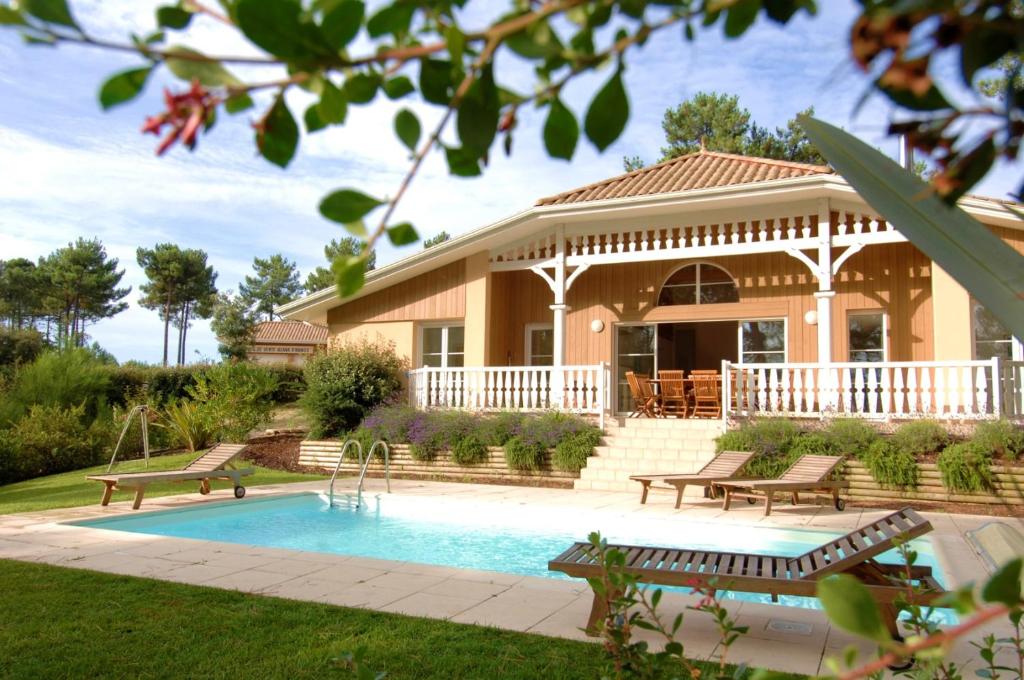 a house with a swimming pool in front of a house at Lagrange Vacances - Atlantic Green in Lacanau-Océan