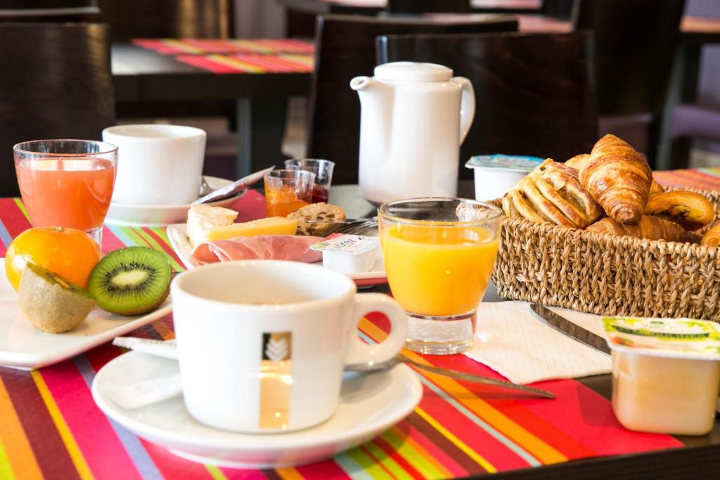 a breakfast table with a basket of bread and orange juice at Le Ceïtya in Saint-Gilles-Croix-de-Vie