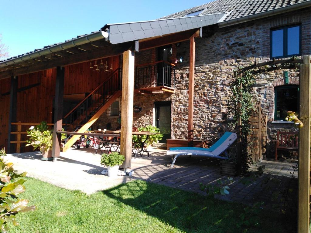 une maison en pierre avec une terrasse et un toboggan bleu dans l'établissement Au Coin des Fagnes, à Jalhay