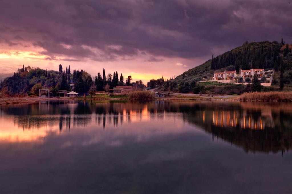 a sunset over a lake with houses and trees at Parathalasso Villas in Monastiraki