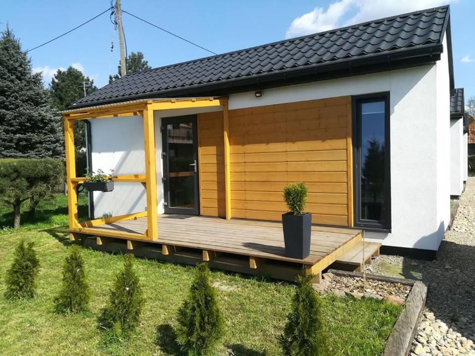 ein kleines Haus mit einer Holzterrasse im Hof in der Unterkunft Domki całoroczne in Zator