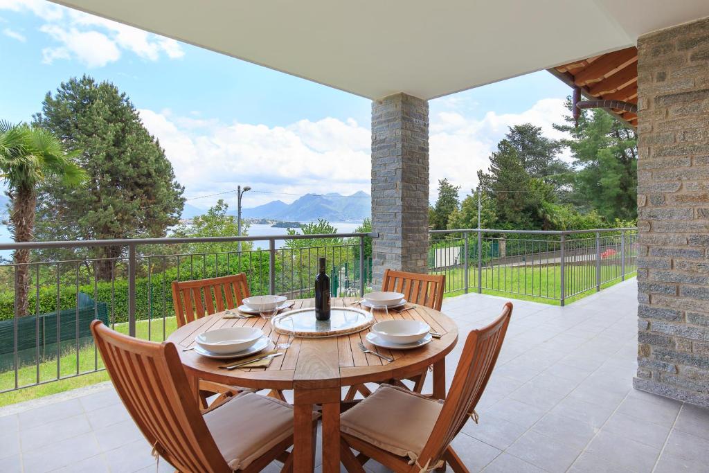een houten tafel met stoelen en een fles wijn bij Baveno Hills | Lakeview apartments in Baveno
