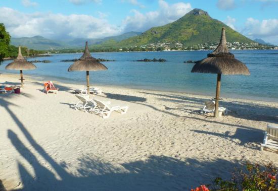 a beach with umbrellas and chairs and the ocean at Arabica Villa in Flic-en-Flac