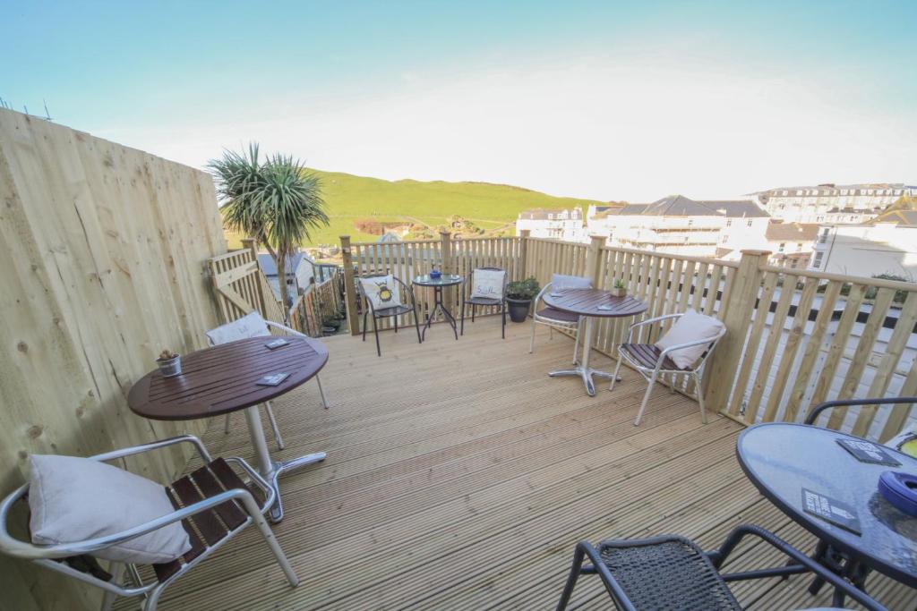 a patio with tables and chairs on a wooden deck at Harcourt Hotel in Ilfracombe