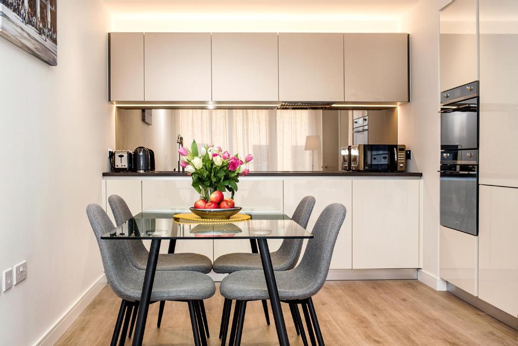a kitchen and dining room with a glass table and chairs at Silver Apartment Kew Bridge London in Kew Bridge