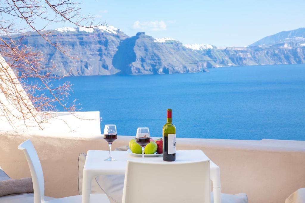 a table with a bottle of wine and two glasses at Opsis Cave House in Oia