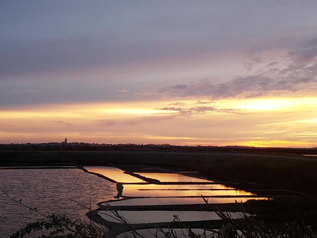 a body of water with a sunset in the background at La Maison Bizienne Guérande in Guérande