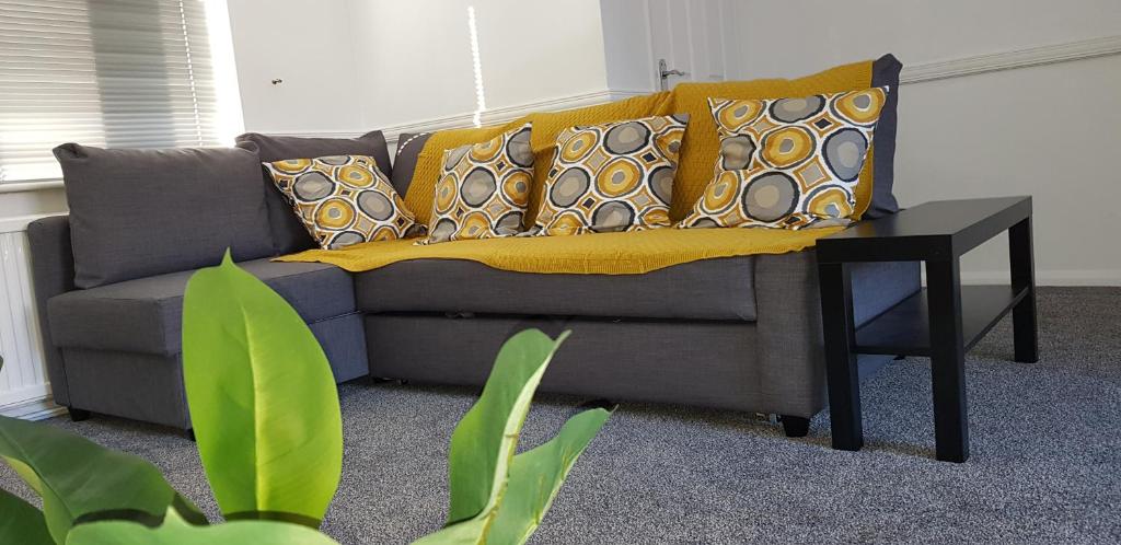 un sofá con almohadas y una mesa en la sala de estar. en Maplewell House en Leicester