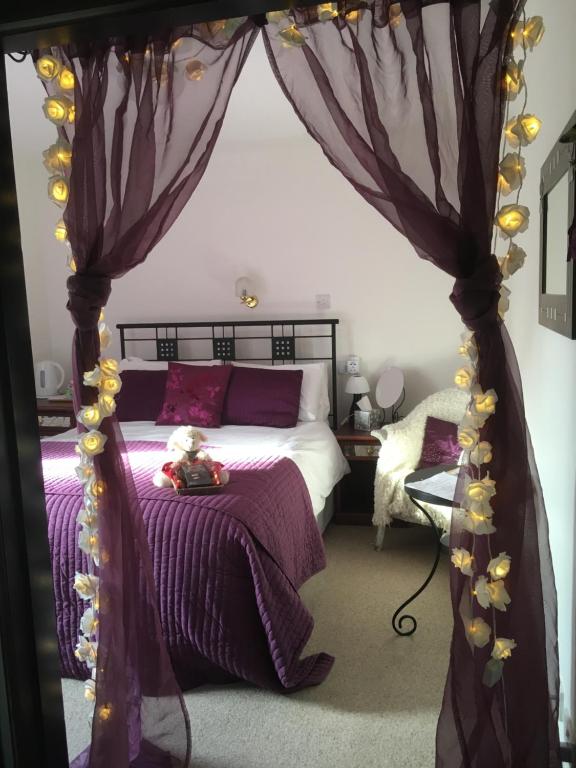 a bedroom with a canopy bed with purple sheets at Gordon House in Tomintoul