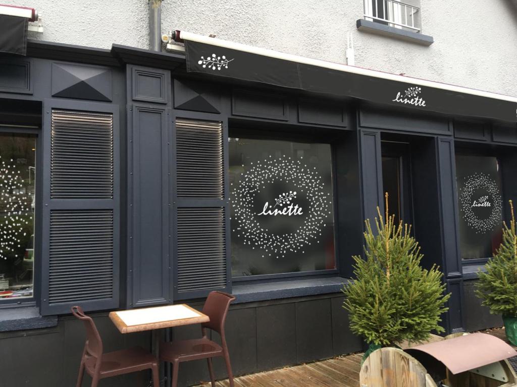 a restaurant with a table and chairs in front of a store at Hotel Linette in Aumont-Aubrac