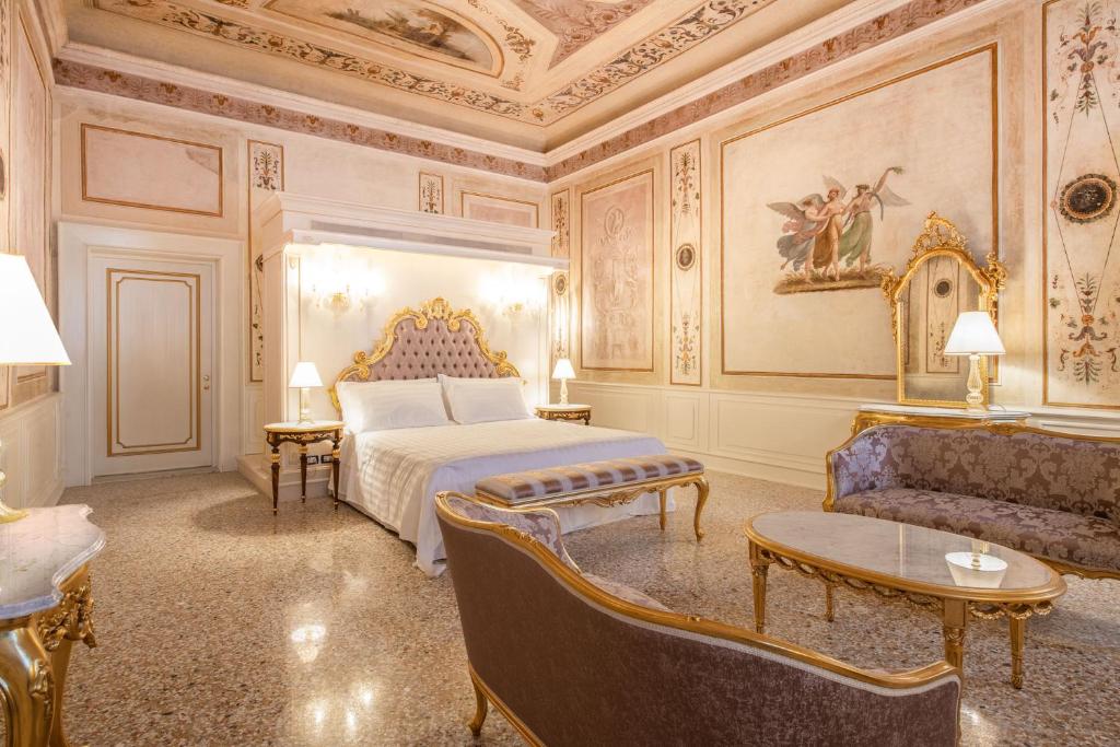 a bedroom with a bed and a couch and a table at Ca' Bonfadini Historic Experience in Venice