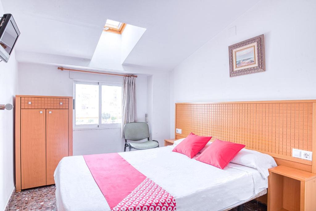 um quarto com uma cama grande e almofadas cor-de-rosa em Hostal Nova Picanya em Picanya