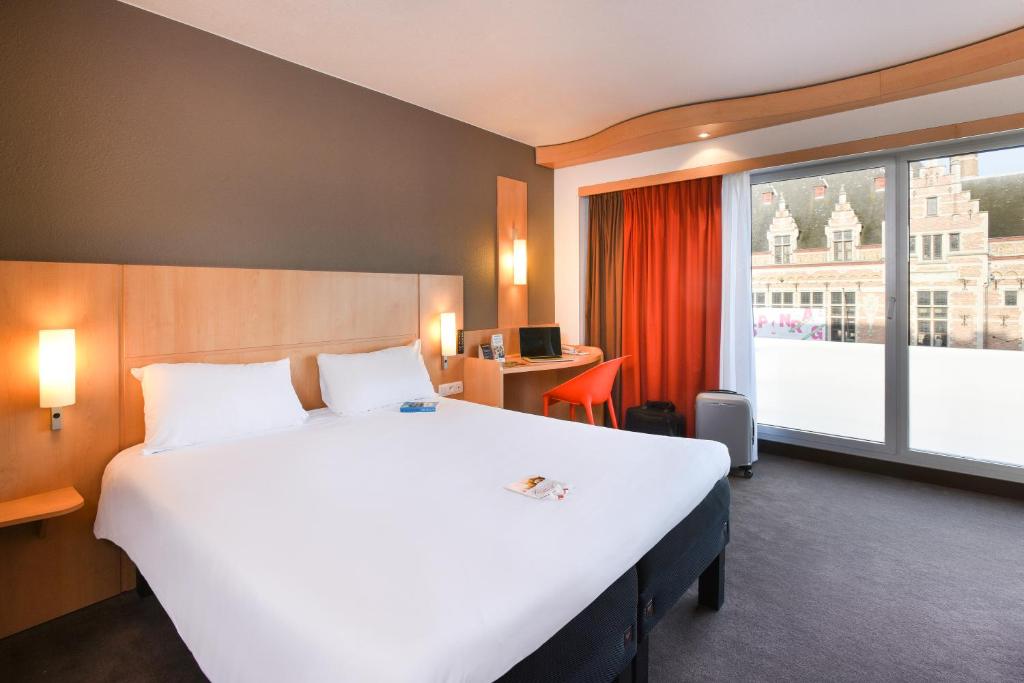 uma grande cama branca num quarto de hotel com uma janela em ibis Kortrijk Centrum em Kortrijk