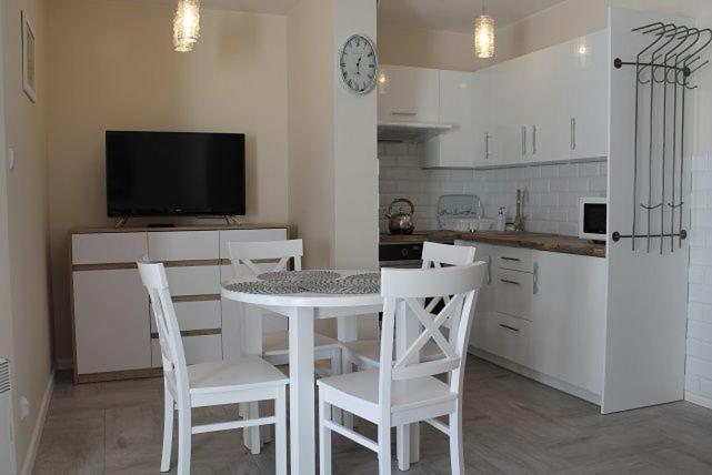 kuchnia ze stołem i krzesłami oraz telewizorem w obiekcie Apartament "Zacisze" w Łukęcinie