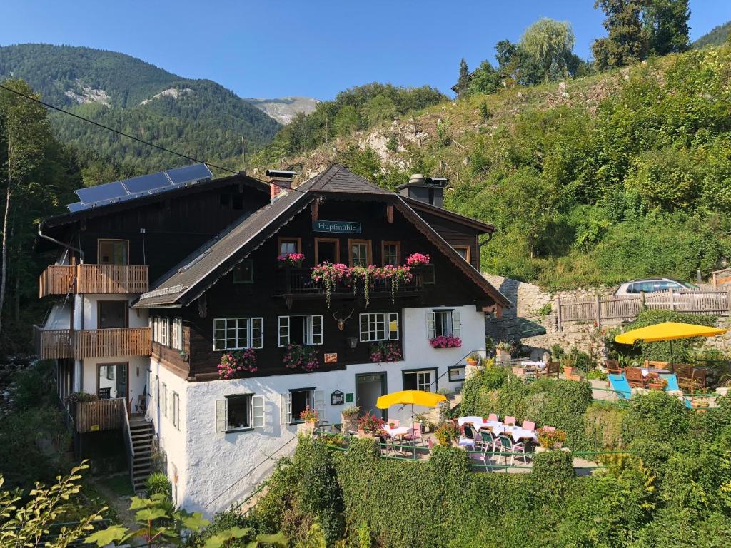 a building with chairs and umbrellas in front of it at Hupfmühle Pension in St. Wolfgang