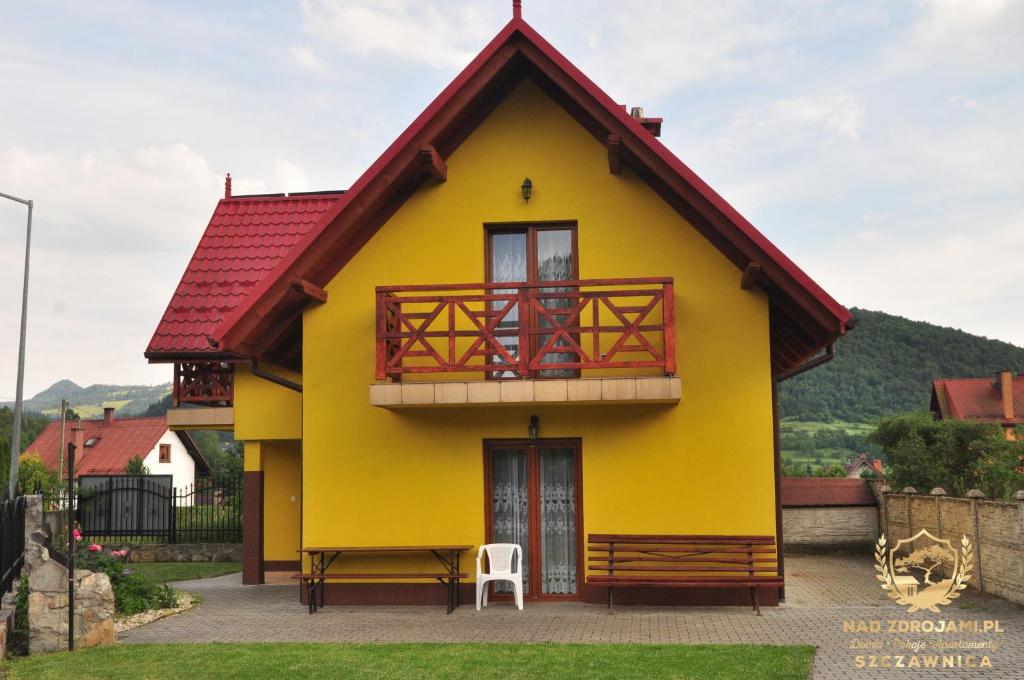 una casa amarilla con techo rojo en "Nad Zdrojami" Domek Sopotnicka 691-739-603 en Szczawnica