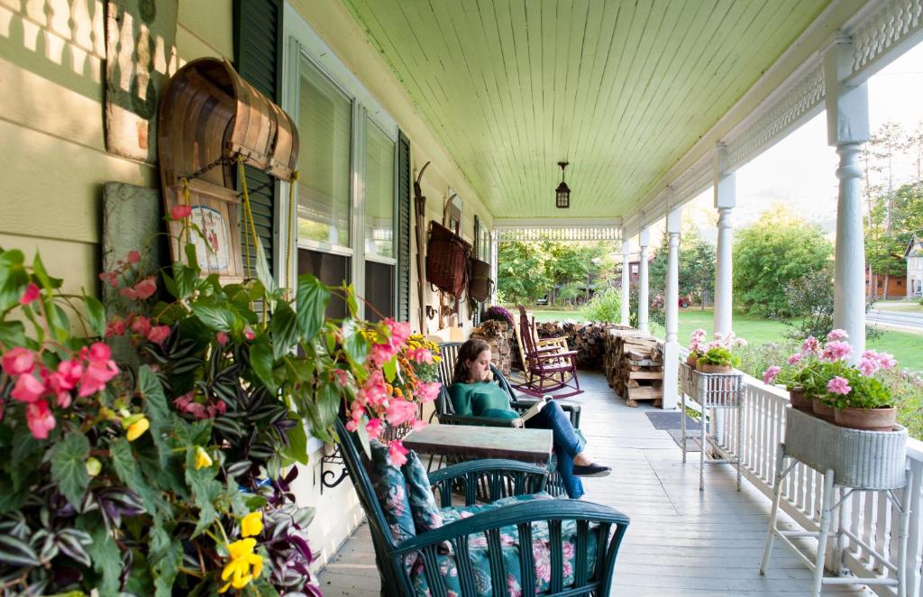 a woman sitting on the porch of a house with flowers at Keene Valley Lodge in Keene Valley
