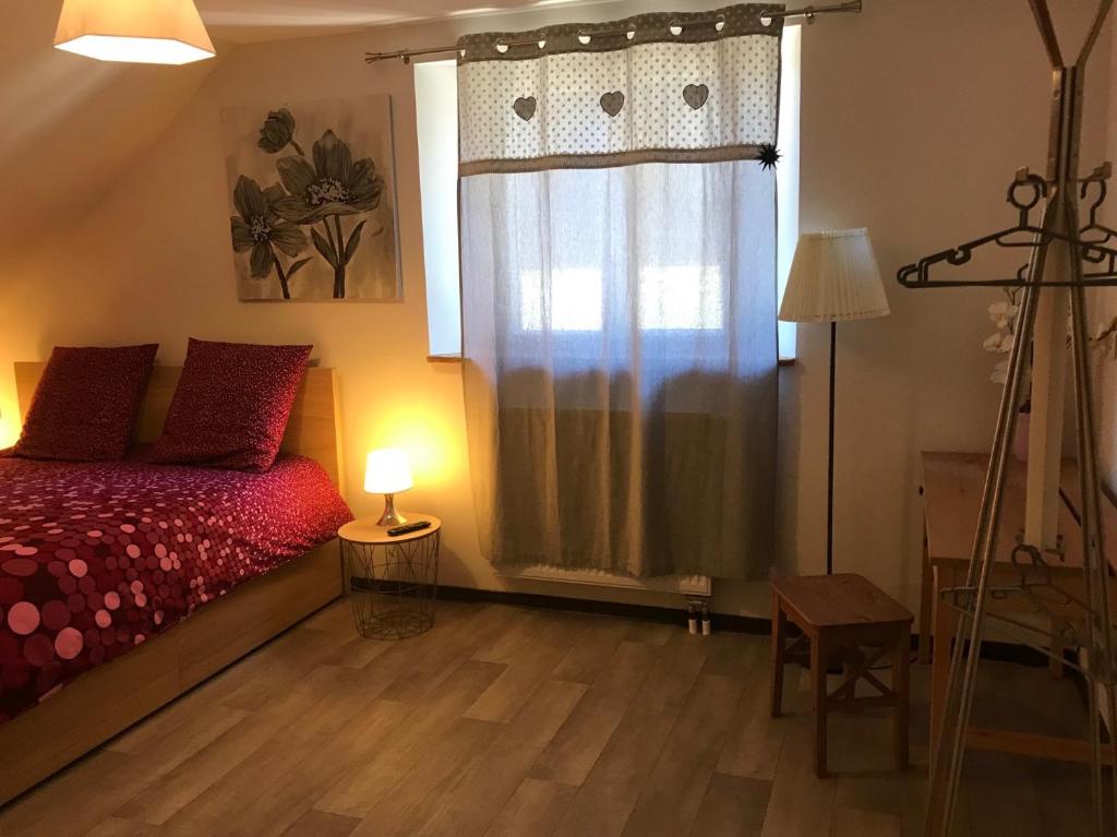 1 dormitorio con cama roja y ventana en Gîte aux deux Hameaux en Saint-Pierre-Bois