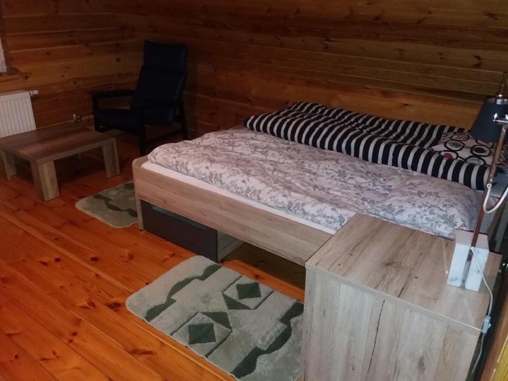 Agroturystyka Rogoznia في Rogóżnia: سرير وكرسي في غرفة بجدران خشبية