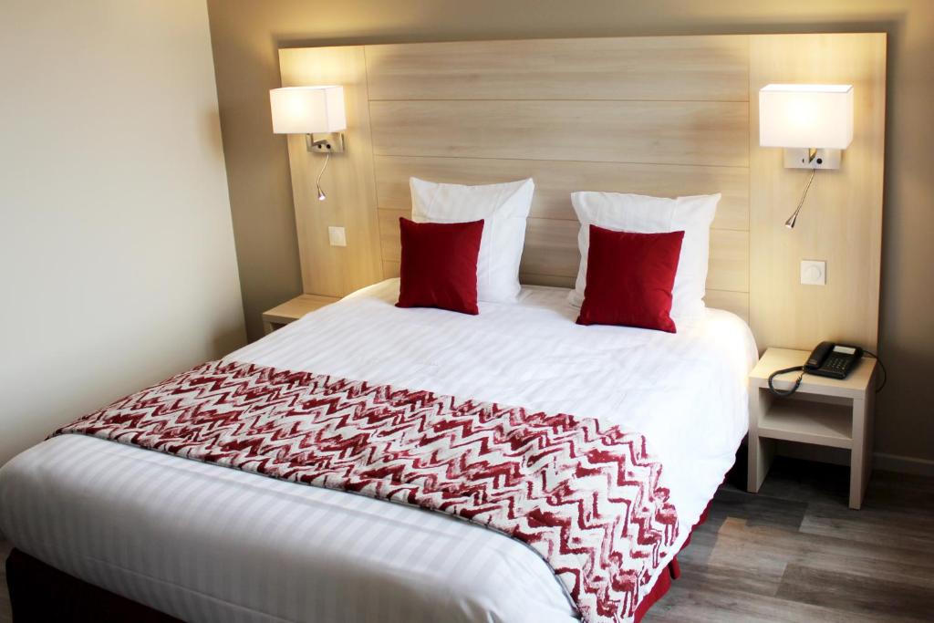 Cette chambre comprend un grand lit avec des oreillers rouges. dans l'établissement Hotel le Vauxois, à Vaux-sous-Aubigny