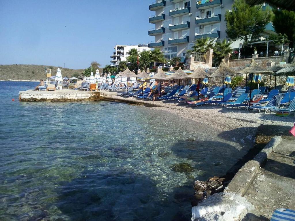 una playa con sillas y sombrillas y un hotel en Korali apartment, en Sarandë