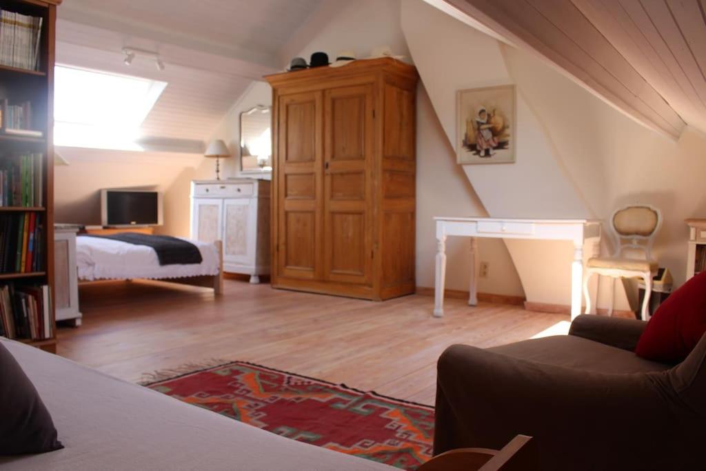B & B Le Jardin Bed & Breakfasts في Ménil: غرفة معيشة مع سرير ومكتب في غرفة
