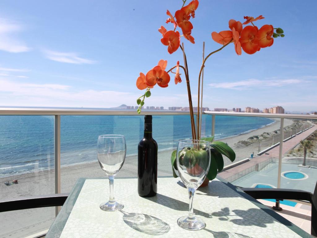 a table with two wine glasses and a vase with flowers at Rentyplus Mar Azul MangaNorte in La Manga del Mar Menor