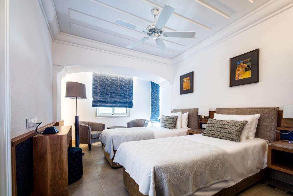 a bedroom with two beds and a ceiling fan at Columbia Beach Resort in Pissouri