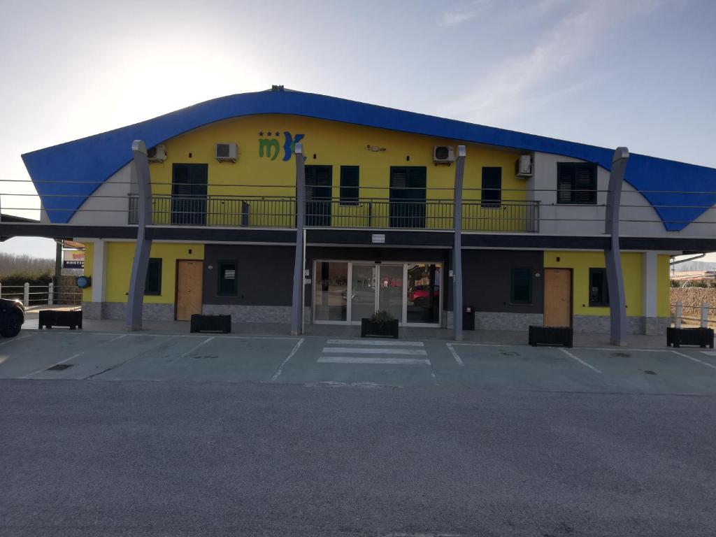 a large yellow building with a blue roof at Motel Kratos in Bisignano