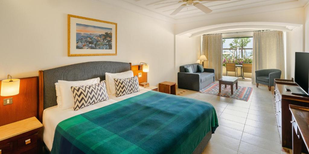 a hotel room with a bed and a television at Columbia Beach Resort in Pissouri