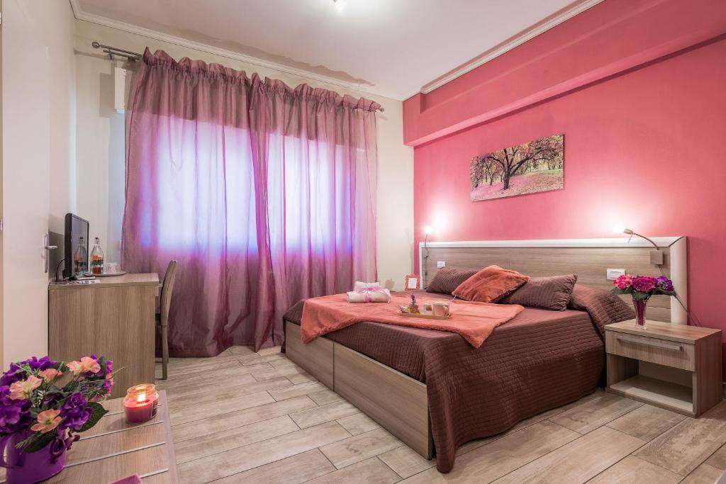Suite Room Fiumicino في فيوميتشينو: غرفة نوم بجدران وردية وسرير مع طاولة