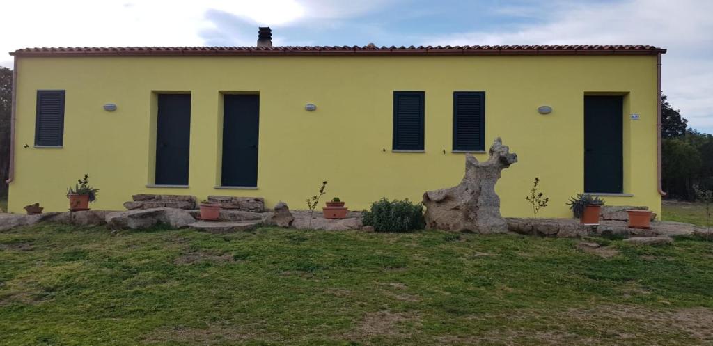 una casa amarilla con un tronco de árbol delante de ella en casa del ginepro Lu sali, en Casagliana
