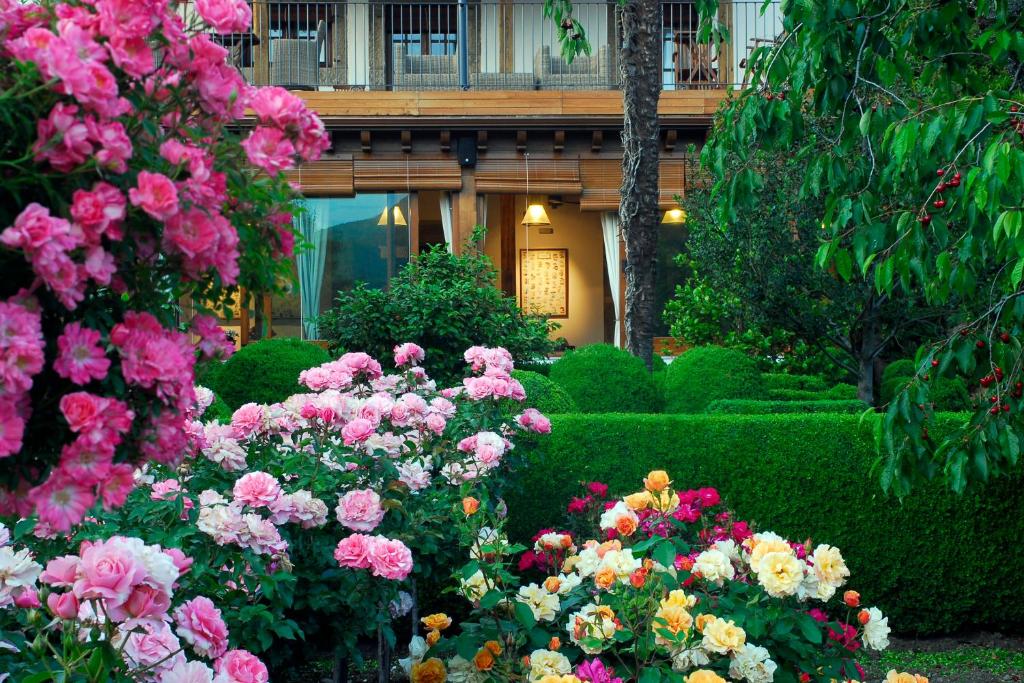 a garden with pink and yellow flowers in front of a building at El Jardín del Convento, Casa Rural in Hervás