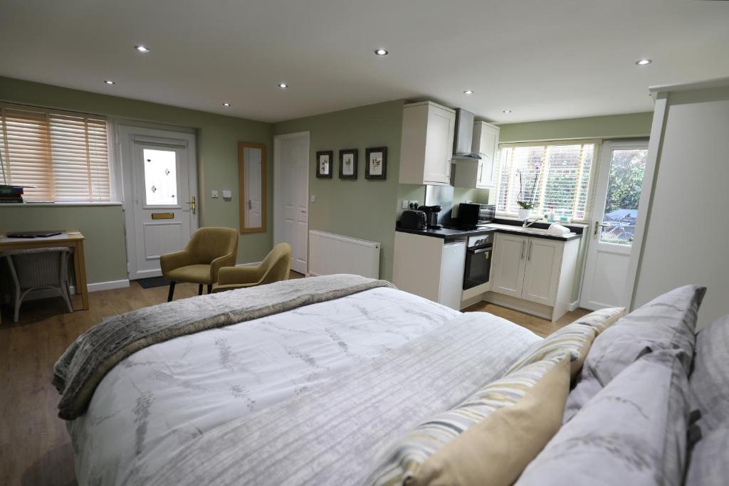 a bedroom with a large bed and a kitchen at Sage Cottage in Bury