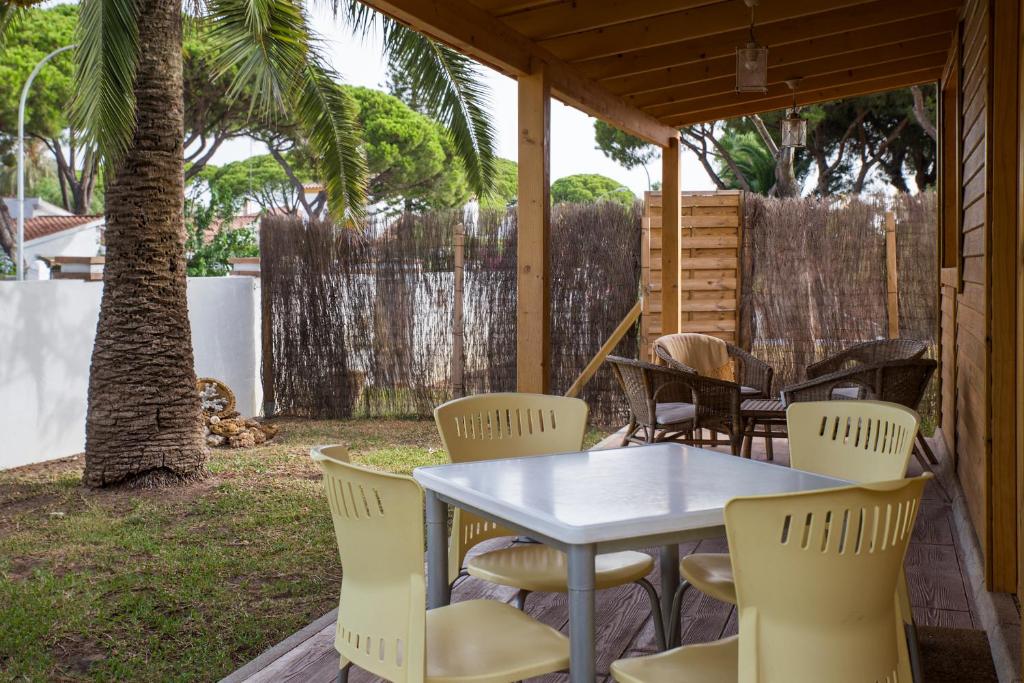 a table and chairs on a patio with a tree at Casita de madera junto al mar in El Puerto de Santa María