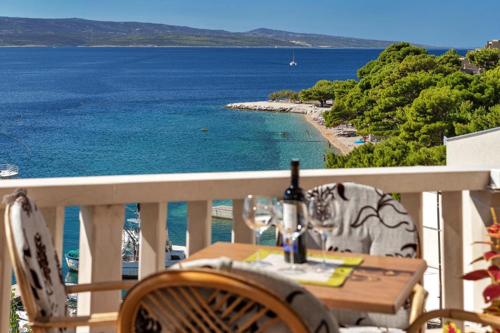 uma mesa com copos de vinho numa varanda com vista para o oceano em Apartmans Lale em Brela