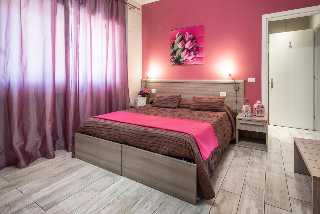 1 dormitorio con 1 cama grande y pared de color rosa en B&B Le Ortensie, en Fiumicino