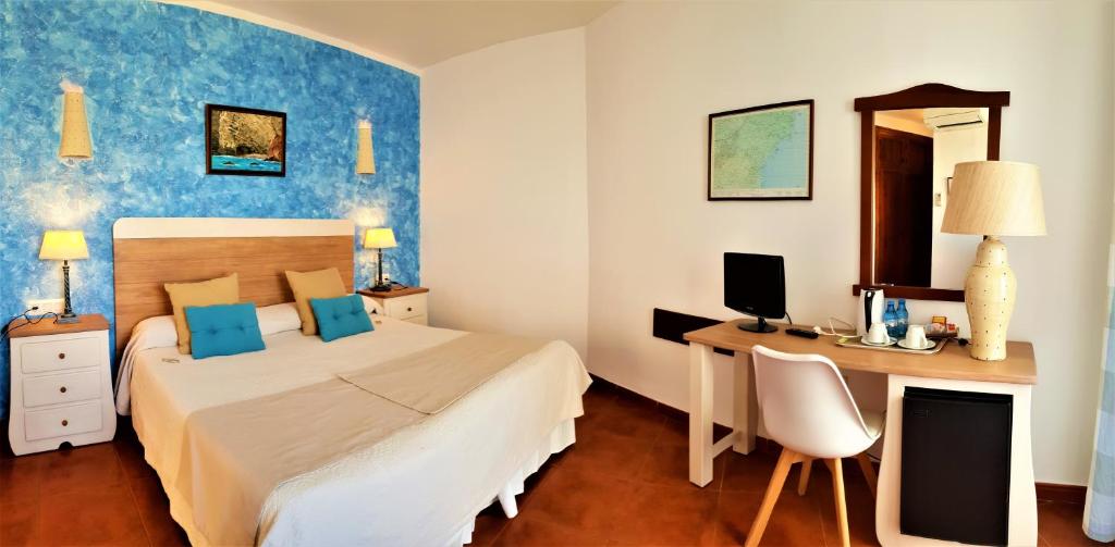 a bedroom with a bed and a desk with a computer at Hotel las Calas in Agua Amarga