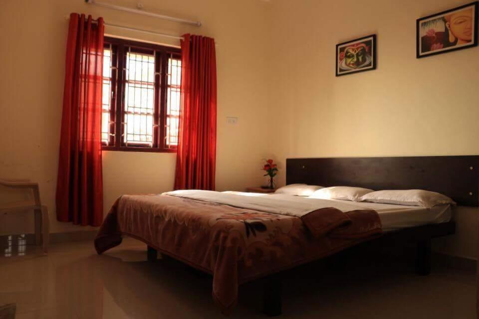 a bedroom with a large bed with red curtains at Skylarc Inn in Ooty