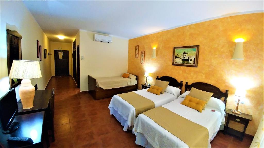 a hotel room with two beds and a couch at Hotel las Calas in Agua Amarga