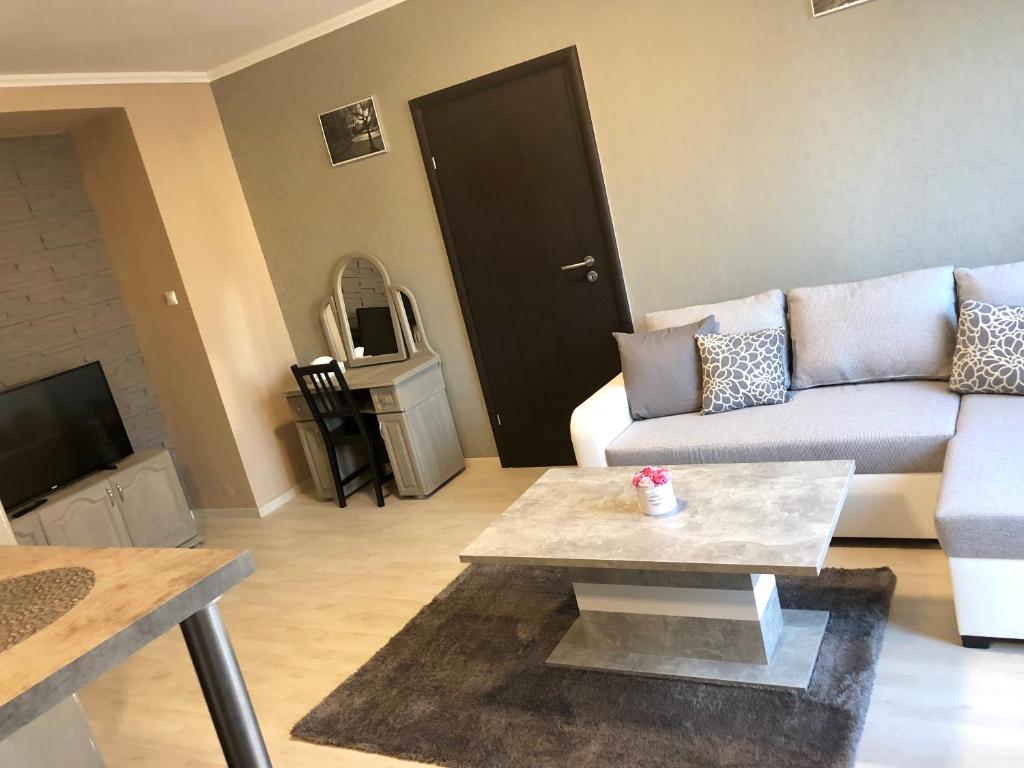 uma sala de estar com um sofá e uma mesa de centro em Sugárút Corner Apartman em Debrecen