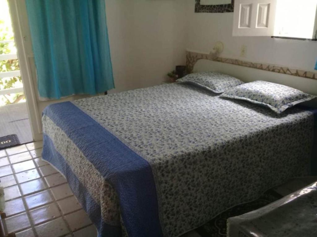 a bedroom with a bed with a blue blanket on it at Chalé 01 em Maragogi Brasil Maragogi in Maragogi