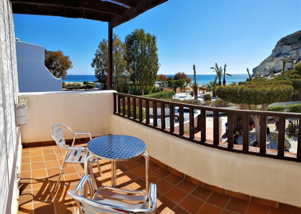 eine Terrasse mit einem Tisch und Stühlen auf dem Balkon in der Unterkunft Hotel las Calas in Agua Amarga