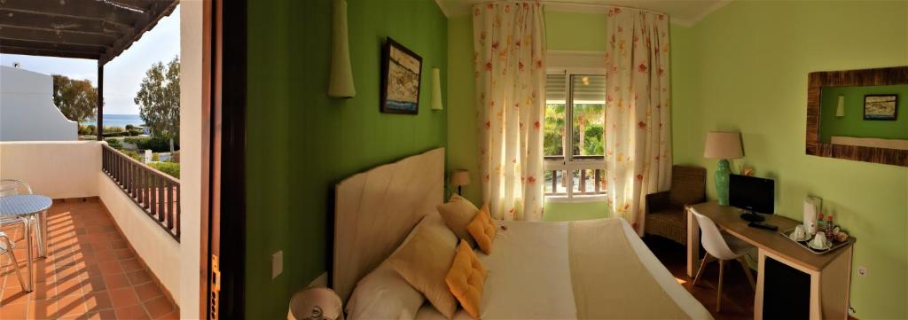 a bedroom with green walls and a bed and a desk at Hotel las Calas in Agua Amarga
