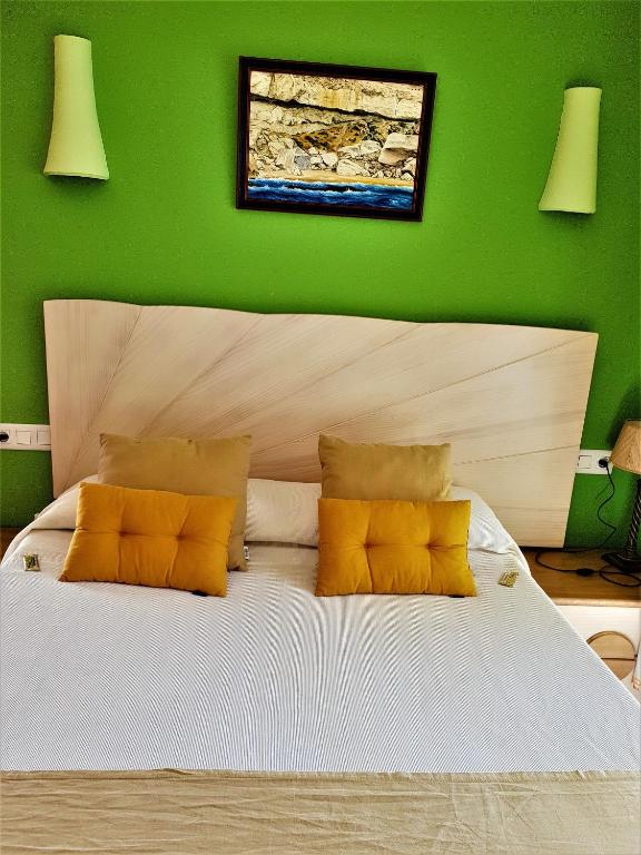 a green bedroom with a large bed with yellow pillows at Hotel las Calas in Agua Amarga