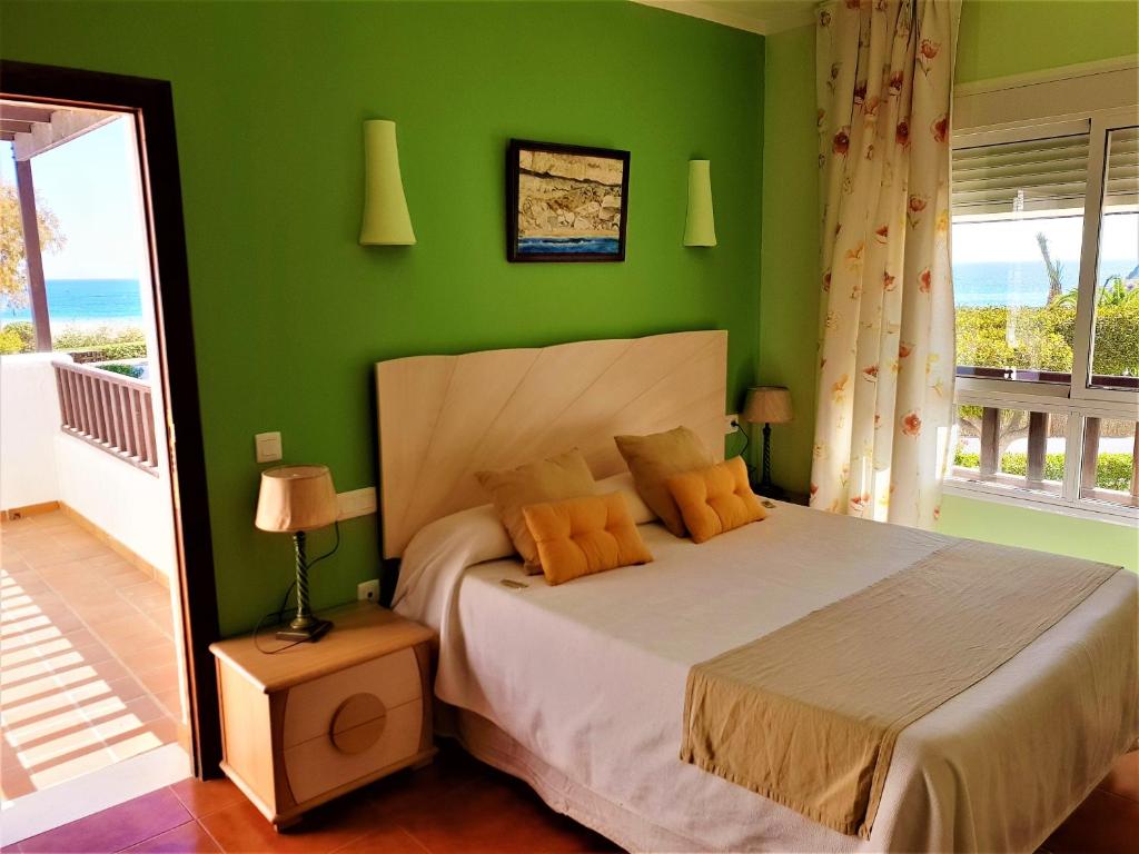 a bedroom with green walls and a bed with orange pillows at Hotel las Calas in Agua Amarga