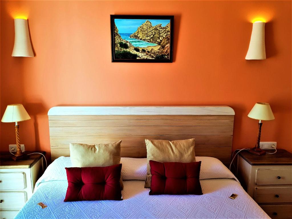 a bedroom with orange walls and a bed with red pillows at Hotel las Calas in Agua Amarga